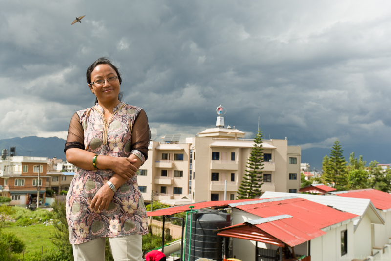 Ms. Aruna Awale-Meteorologist for the Alternative Energy Promotion Center in Kathmandu poses for a picture. In the background is a wind turbine provided by MEC.