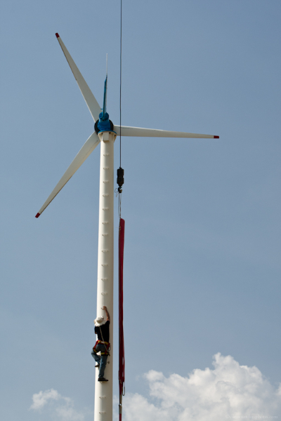 A worker climbs the mast of a 10KW wind turbine on the King's Wind Farm in Thailand. The farm is owned and operated by Prapai Technologies.